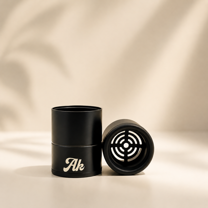 Black cylindrical air filter with 'Ak' branding on a beige fabric background