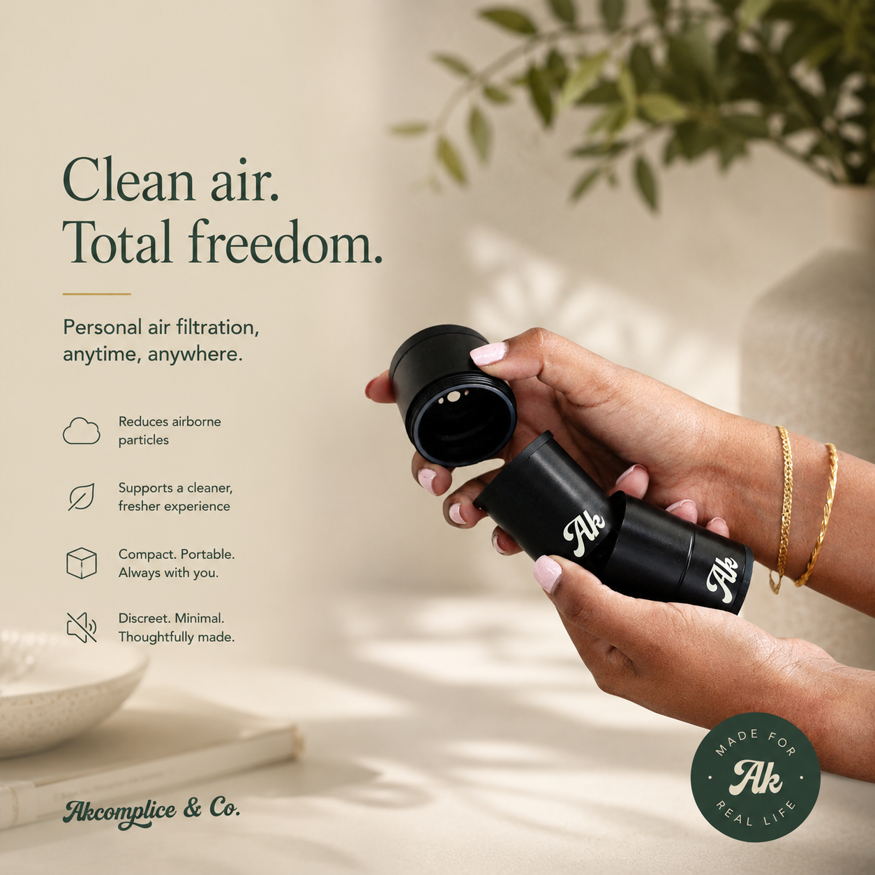 Hand holding a black personal air filtration device with text about clean air and freedom, set against a neutral background.