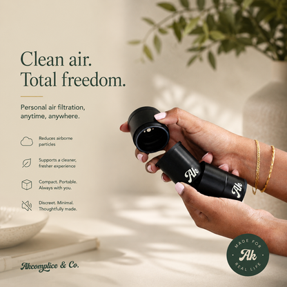 Hand holding a black personal air filtration device with text about clean air and freedom, set against a neutral background.